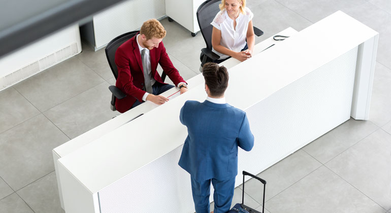 Guest services agent of Prague City Apartments greeting older man at the management office